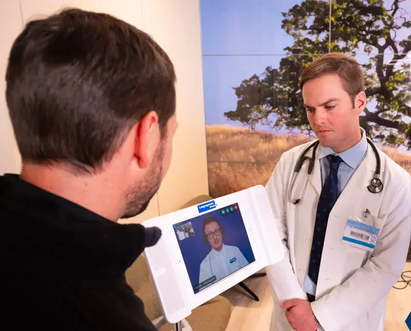 A doctor and patient in a medical setting speak with a LanguageLine video interpreter